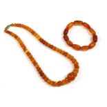 An Art Deco single row graduated half bead shaped amber bead necklace, with central circular bead,