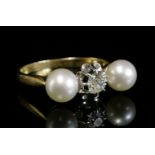 A three stone diamond and cultured pearl ring,with a cushion cut diamond, claw set to a white