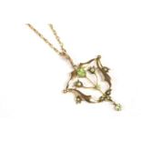 An Edwardian gold peridot and split pearl open frame pendant, marked 9ct, on a gold faceted trace