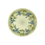 A William Moorcroft Grape and Leaf plate, with blue grapes on a pale green ground, signed and