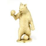 A carved ivory figure of a bear, late 19th Century, stood on his hind legs holding a ball, and on