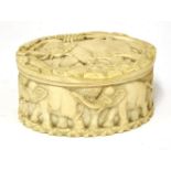 An oval ivory tusk section box, carved with elephants, 11cm long, 5.5cm high