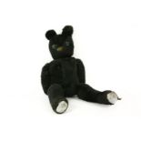 A black plush teddy bear with green glass eyes