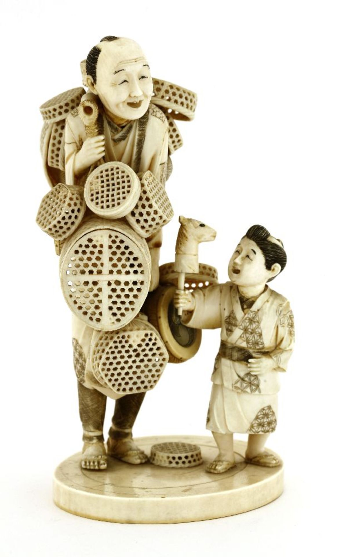 A Japanese ivory okimono,c.1920, of a basket seller, with a bamboo yoke hung on his shoulder with