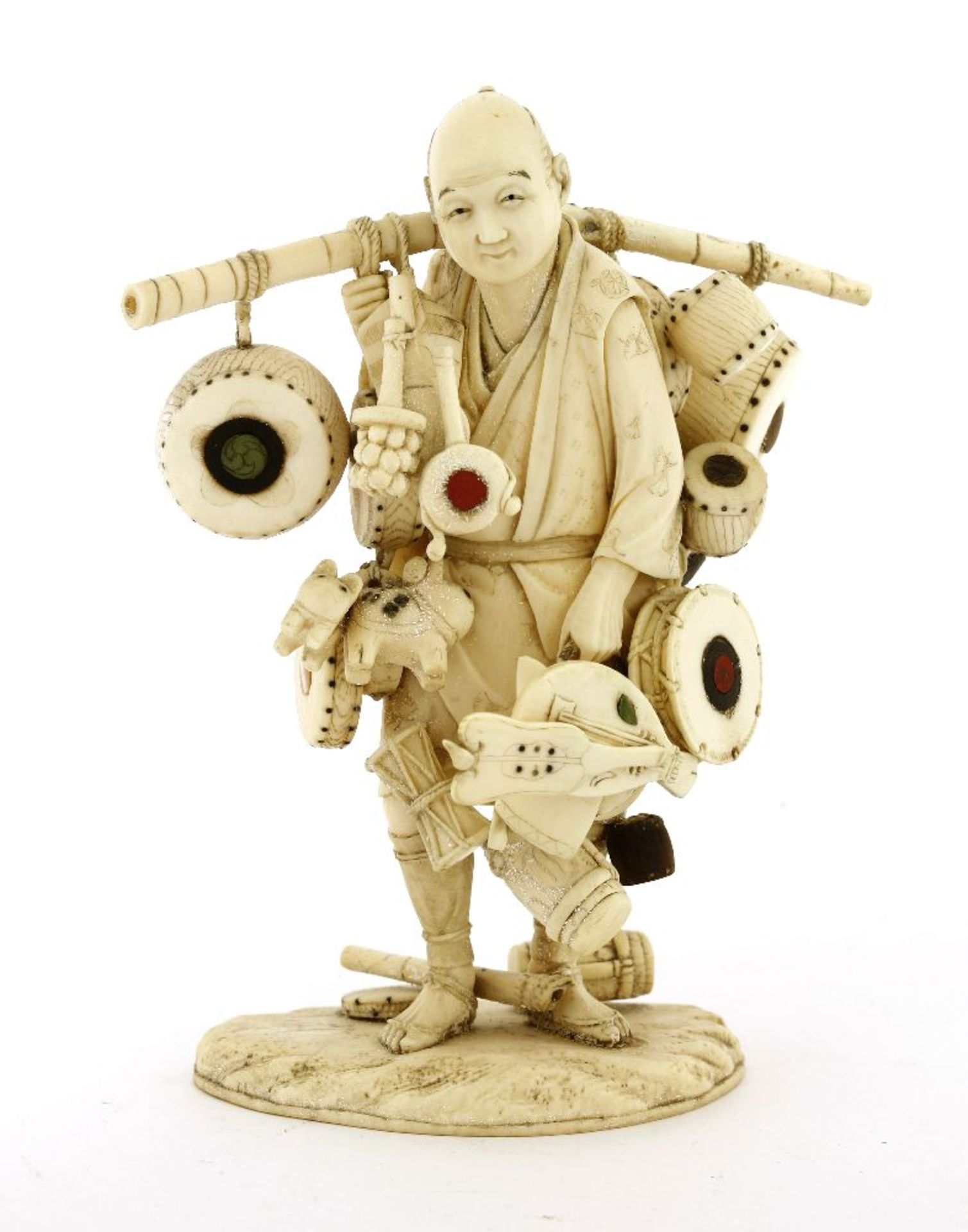A Japanese ivory okimono,Meiji period (1868-1912), of a merchant carrying goods to sell, including