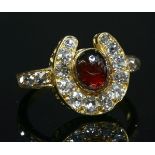 A Victorian gold, garnet and diamond horseshoe ring, with an oval cabochon garnet, rub set to the