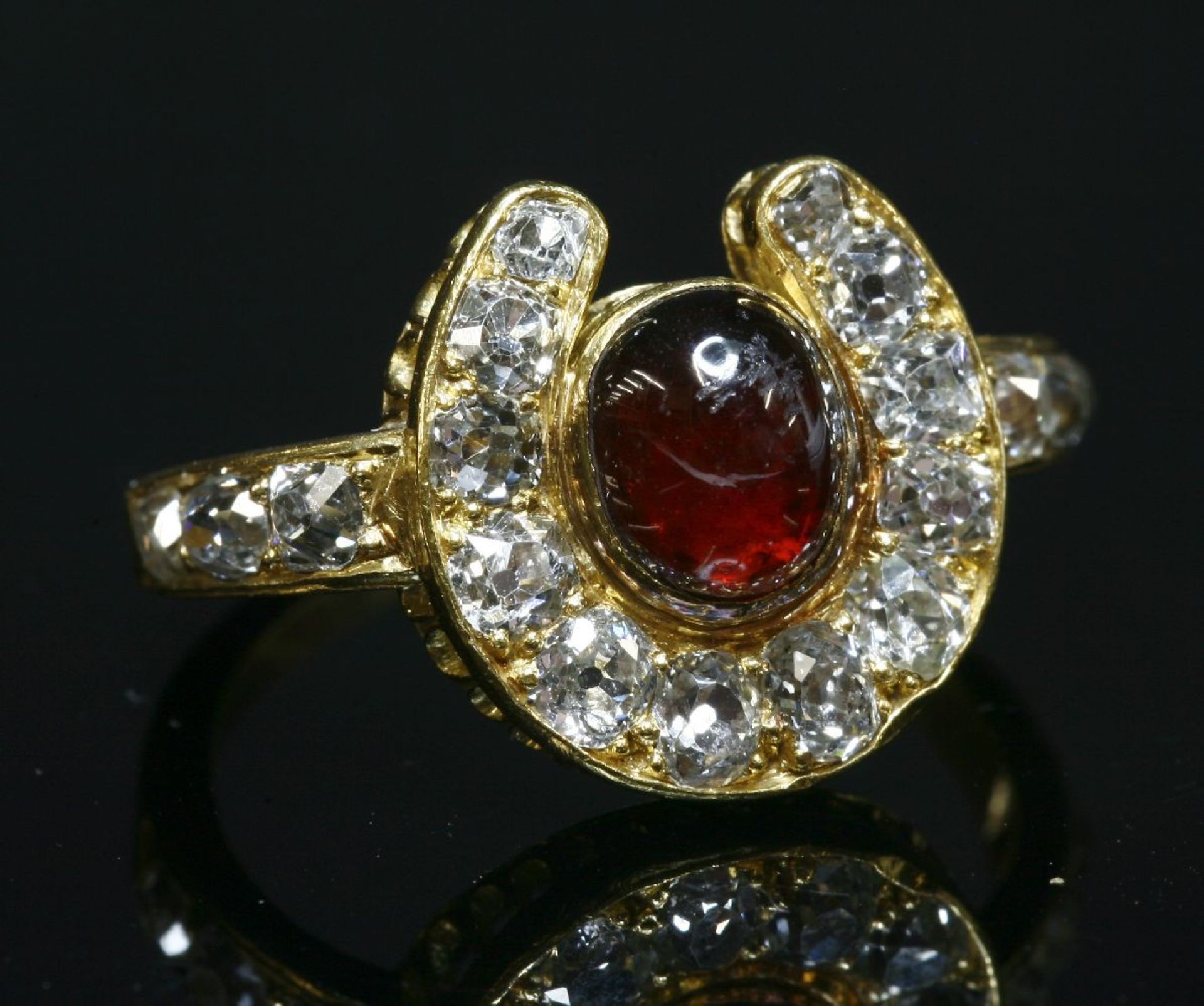 A Victorian gold, garnet and diamond horseshoe ring, with an oval cabochon garnet, rub set to the