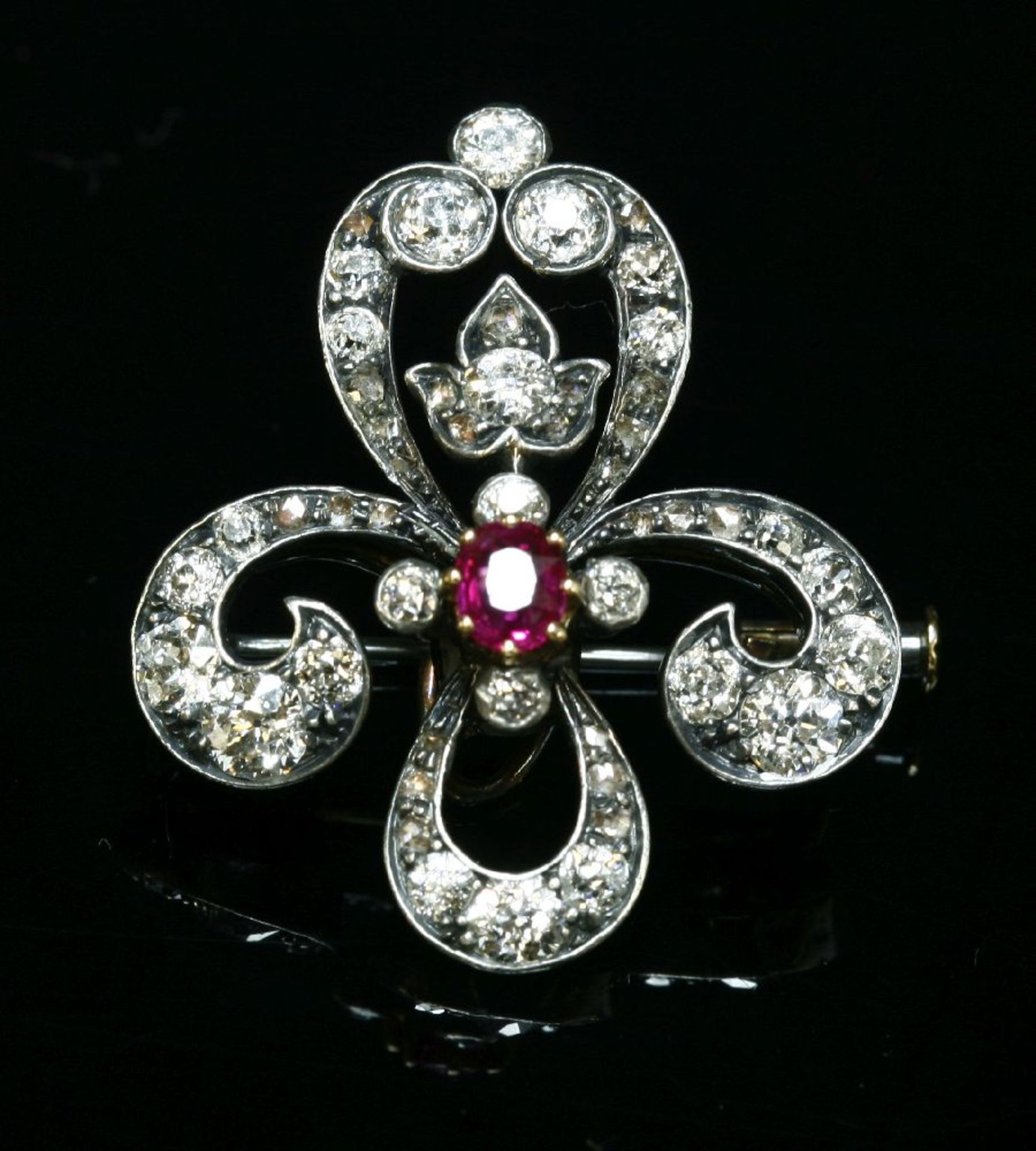 A Continental ruby and diamond fleur-de-lys brooch, c.1890,with an oval Swiss cut ruby, claw set