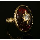 A diamond and garnet ring,with an old European cut diamond, grain set to a gold star, mounted to the