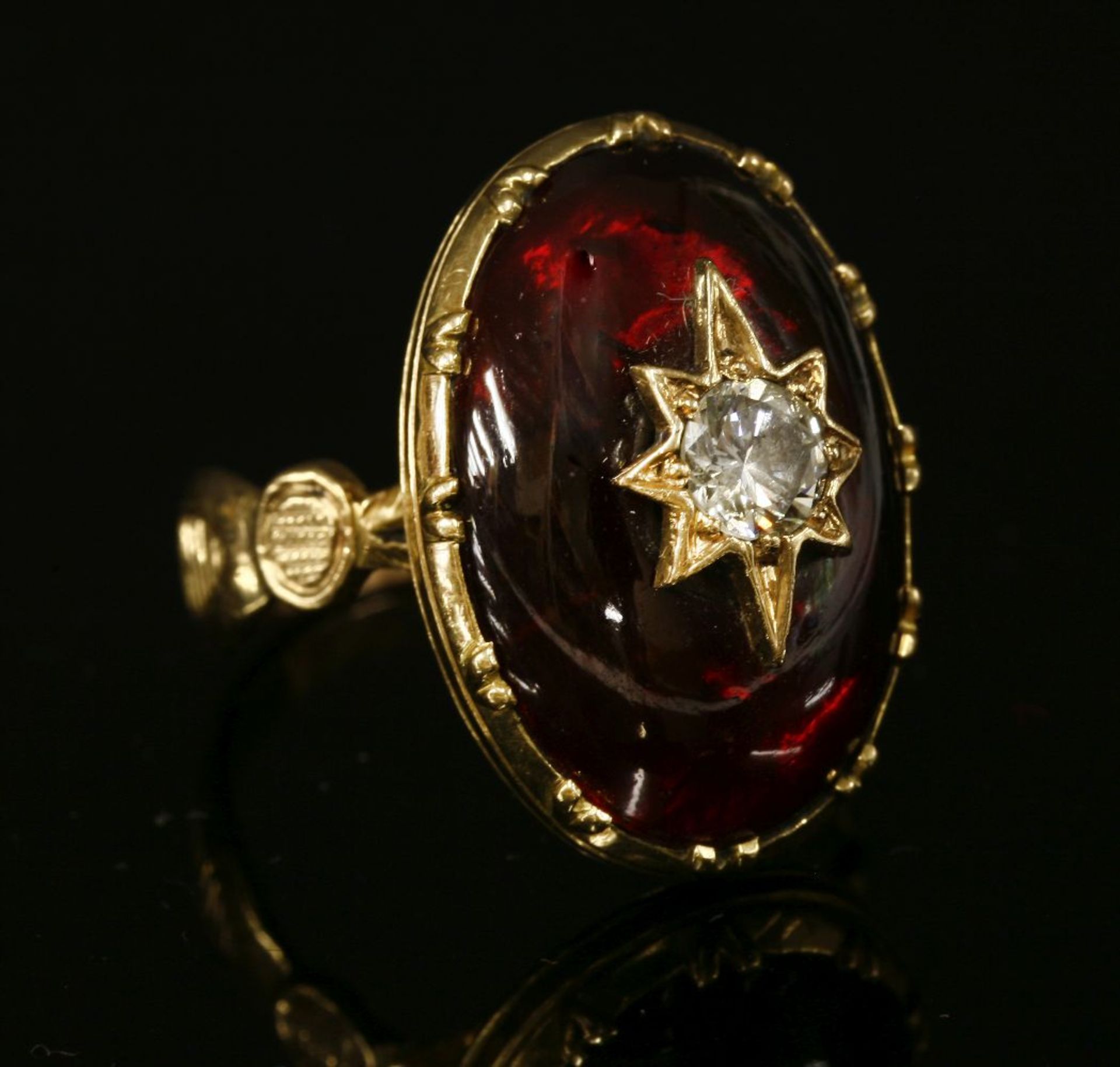A diamond and garnet ring,with an old European cut diamond, grain set to a gold star, mounted to the