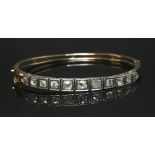 A cased late Victorian diamond set bangle, with a row of graduated old European cut diamonds, each