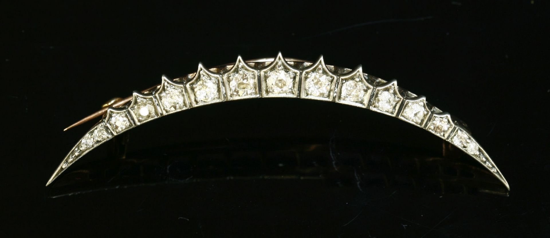 A late Victorian diamond crescent brooch, c.1890,with a row of graduated old European cut and old