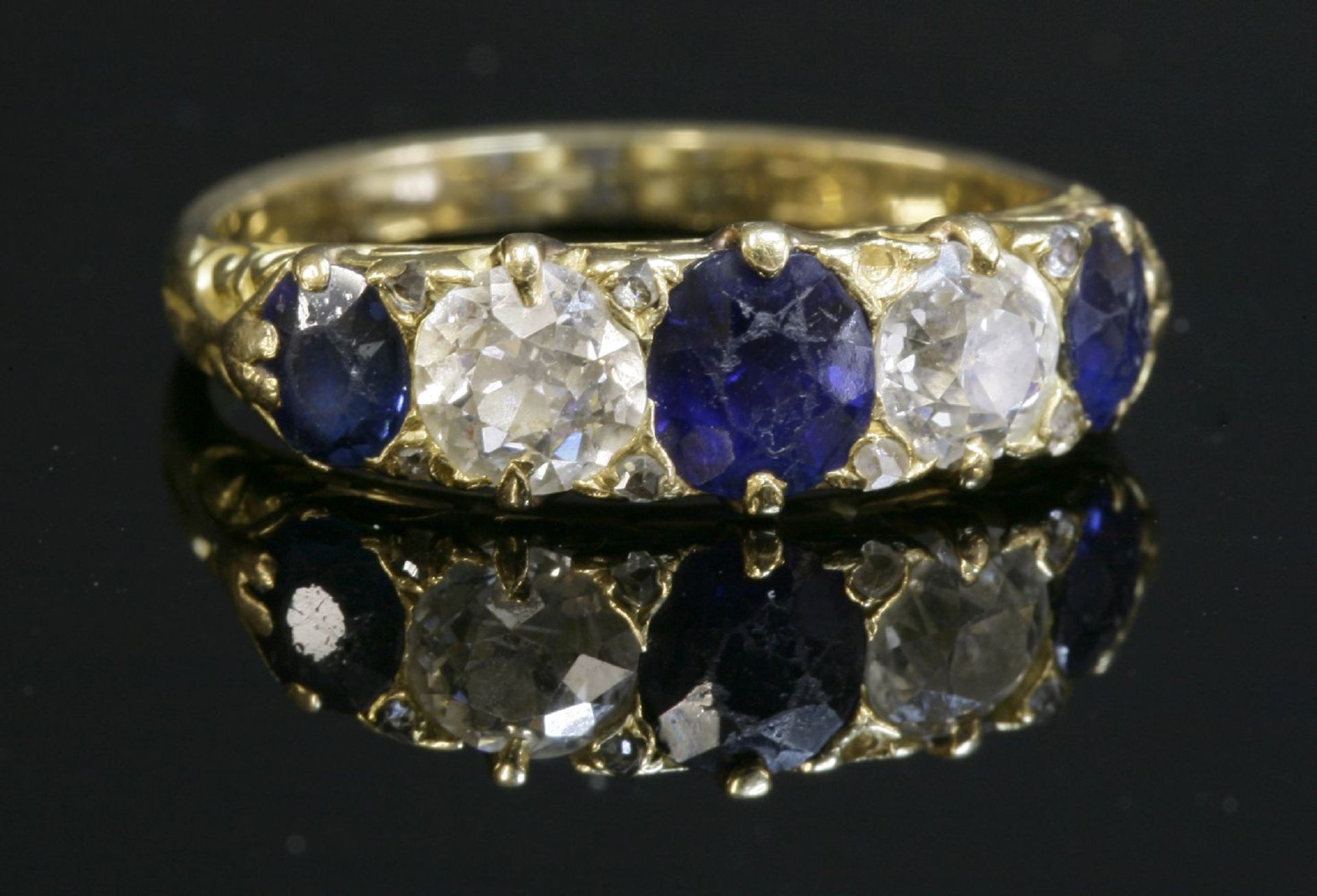 A late Victorian sapphire and diamond carved head ring, with three oval mixed cut sapphires and