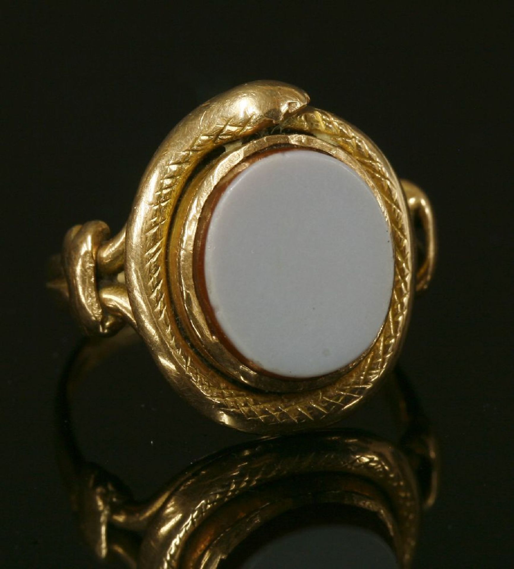 A gold sardonyx ouroboros ring,with a flat section open sardonyx tablet, rub set to a coiled snake