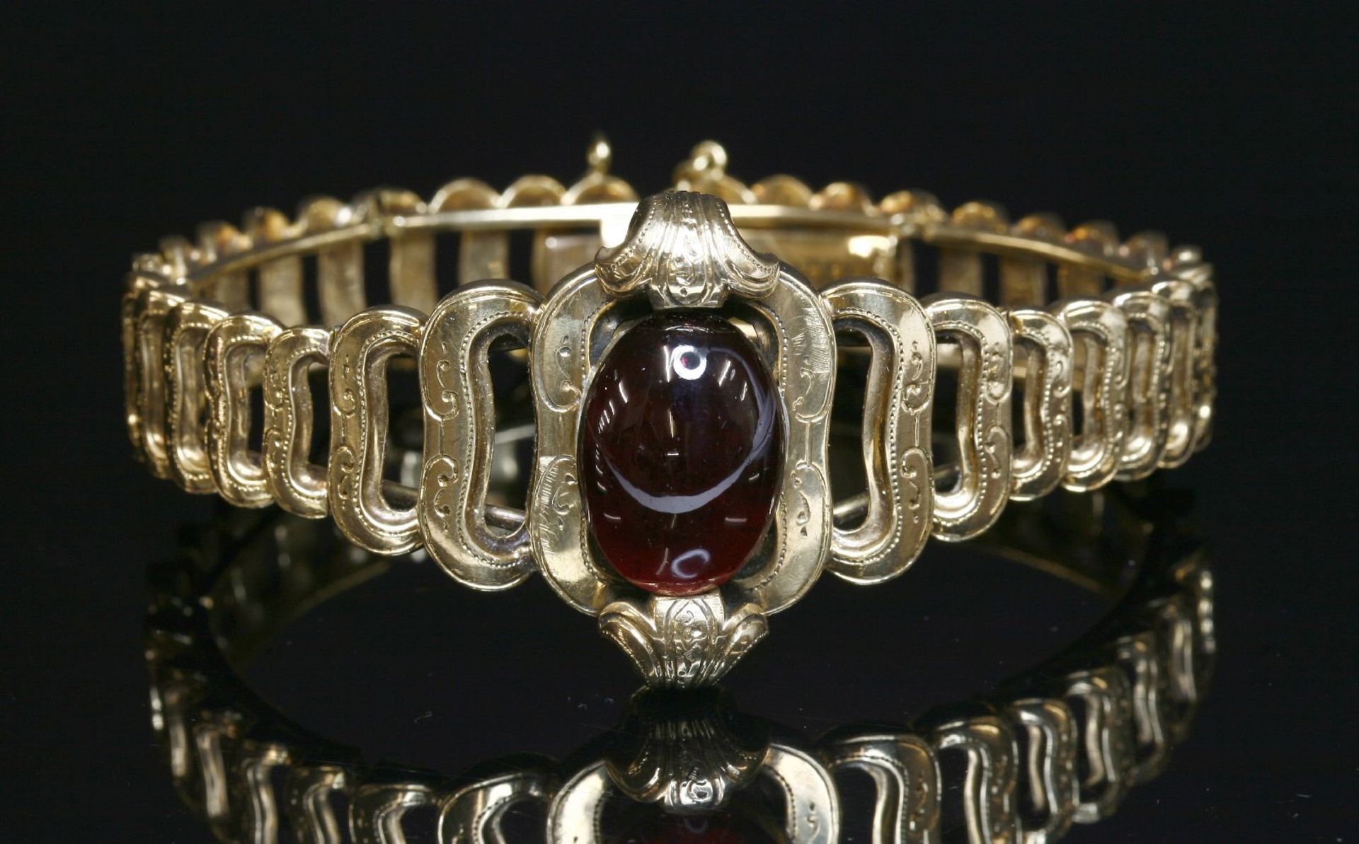 A French gold garnet set bracelet, c.1850,with an oval cabochon garnet, end set to the centre with