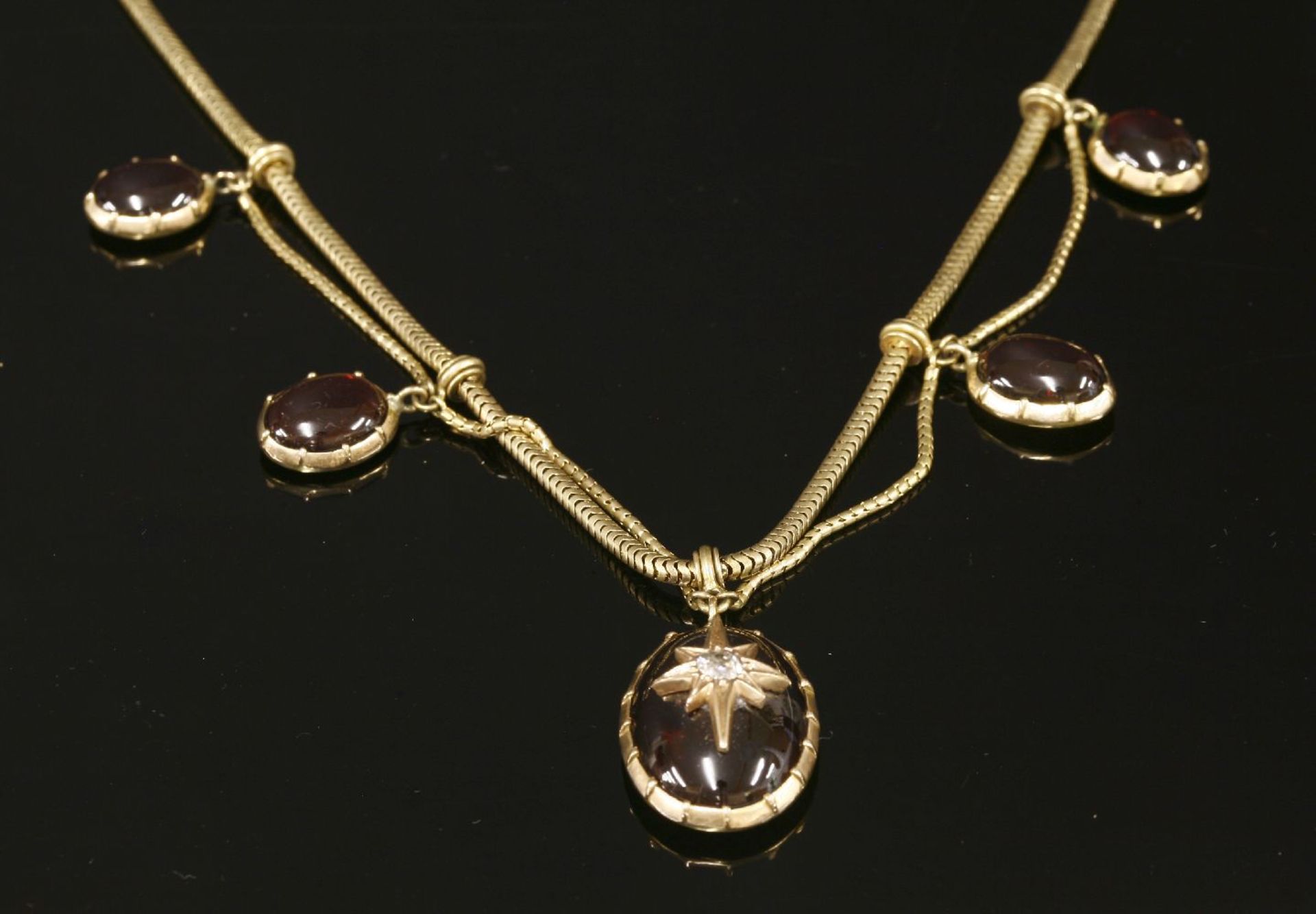 A Victorian gold garnet and diamond swag necklace, c.1860,with five oval graduated cabochon garnet