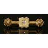 A Victorian gold Etruscan Revival, single stone, diamond dumb-bell bar brooch, c.1870,with a plain