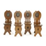 A set for four George II mahogany hall chairs, each of sgabello form, centred with the Flood