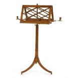 A Regency satinwood duet stand,with latticework rests and brass candle sconces both sides, a rise/
