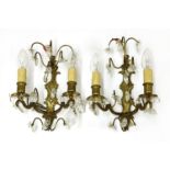 A pair of brass and cut glass two-branch wall lights,20th century, each having a shaped backplate