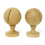 A pair of turned oak balls,on turned oak socles,each 32cm high (2)