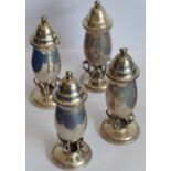 An unusual set of four Arts and Crafts style baluster-shaped pepperettes;