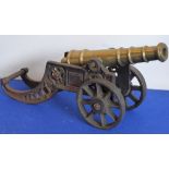 A heavy brass cannon upon a pierced cast iron carriage with spoked wheels,