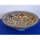 A large pottery bowl decorated with a tin-glaze style Islamic polychrome pattern,