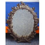 A 19th Century oval wall hanging looking glass having hand bevelled plate and patinated iron frame