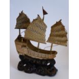 An early 20th century model of a Chinese junk (probably silver gilt) upon a carved wood stand