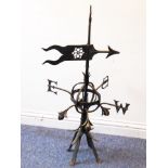 A wrought iron weather vane; pierced arrow head above E,