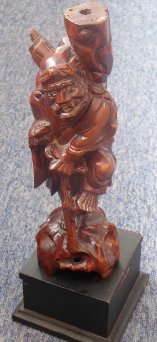 An early 20th century Chinese carved patinated hardwood model of a figure digging with a spade-like