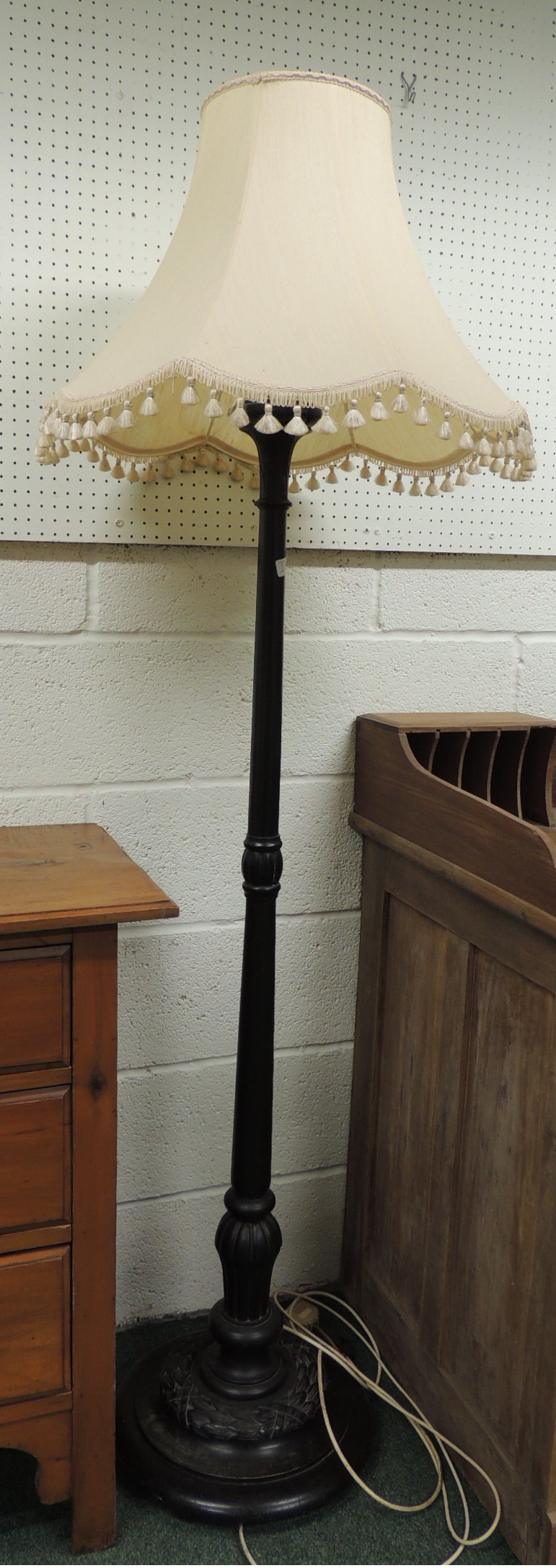 A 20th century ebonised standard lamp with carved laurel leaf decoration to the base, 144cm high.