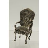 A 19th Century German Hanau miniature silver chair with embossed decoration, the back with putto