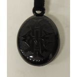 A Victorian jet oval locket with engraved interlocking initials to both sides, opening to reveal