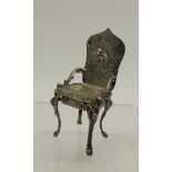 A 19th Century German Hanau miniature silver chair with embossed decoration, the back with a putto