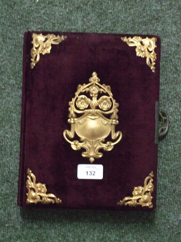 An empty decorative photograph album with velvet and gilt decoration to the cover.