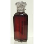 A Victorian ruby glass scent bottle with embossed, hinged silver cover and faceted body, 10.5cms