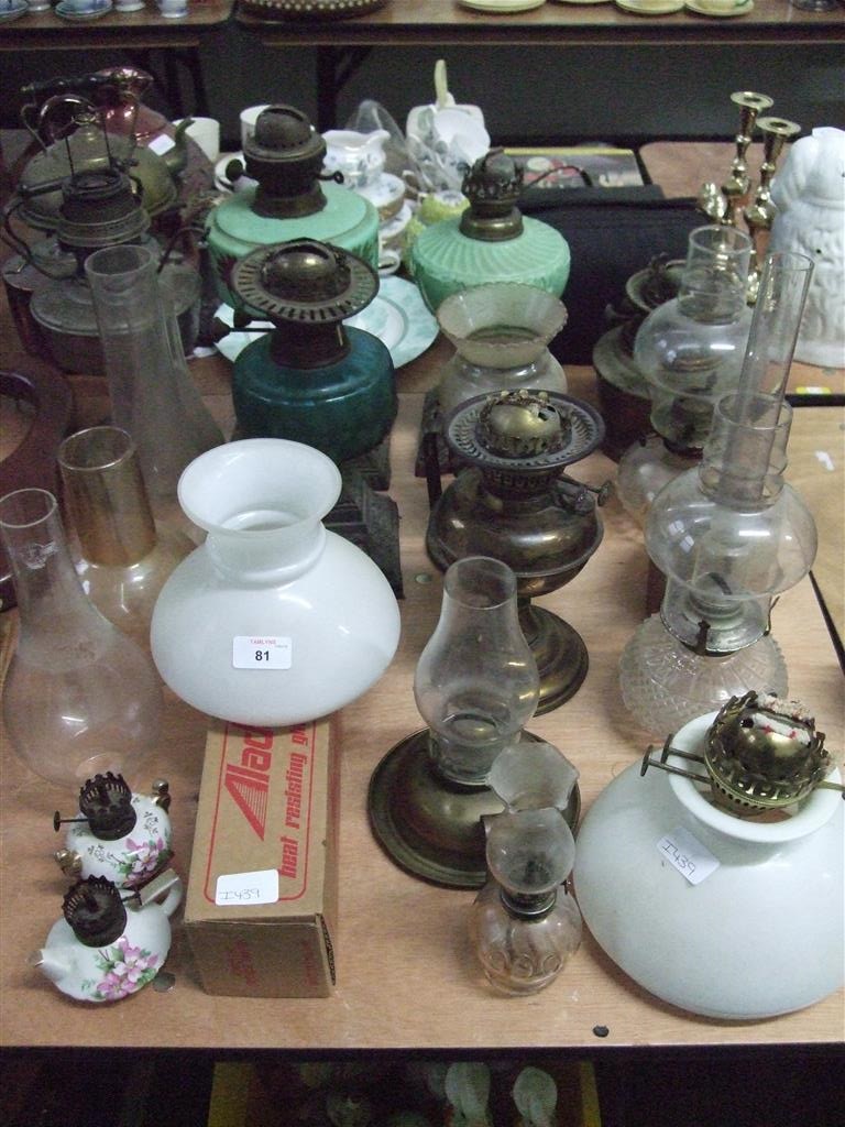 A turquoise glass oil lamp base together with a collection of other oil lamps and shades.