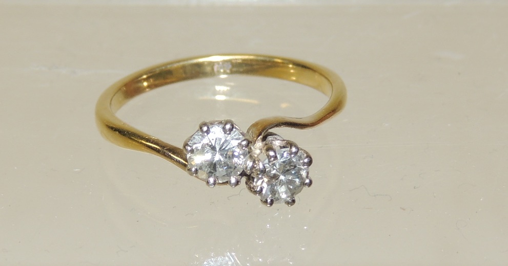 An 18ct gold two stone diamond cross-over ring, each diamond just under half a carat, size S.