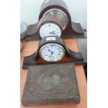 A decorative metal box in the shape of a book and three mantle clocks.