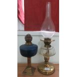 An oil lamp with blue glass lacking shade and chimney together with another oil lamp.