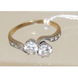 A 9ct gold dress ring, set with two clear paste stones in crossover form, small stones to the