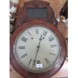 A decorative wall hanging clock with carved wood base, with Roman numerals to the dial.