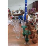 A tall decorative blue glass vessel and stopper together with a pair of green glass vases and