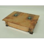 An Arts and Crafts copper box of rectangular form with applied embossed strapping set with Ruskin