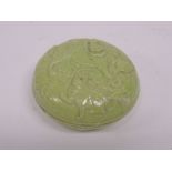 A small Chinese light green glazed circular container and cover, the cover moulded with well