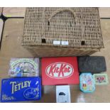 A wicker picnic basket containing assorted tins.