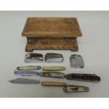 Three Ronson cigarette lighters and a quantity of pen knives contained in a small carved wood box