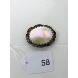 An oval mother of pearl brooch, set in filigree gild.